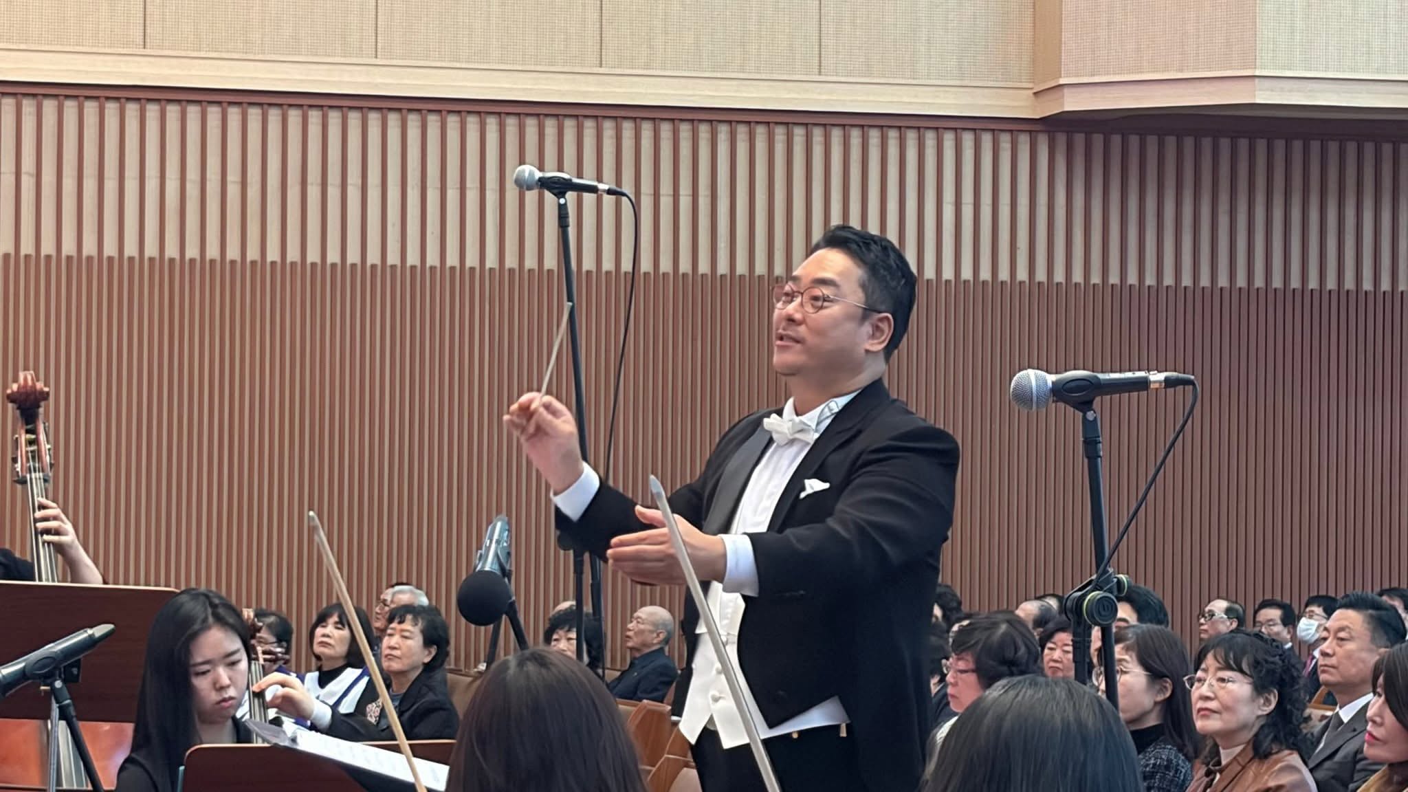 연미복을 입고 오케스트라와 합창단을 지휘하는 모습